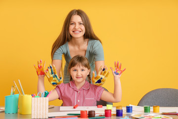 Fototapeta premium Drawing teacher giving private art lessons to little girl on color background