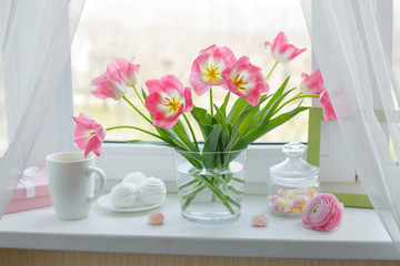 a vase of flowers is on the window a Cup of tea marshmallows, a good morning card