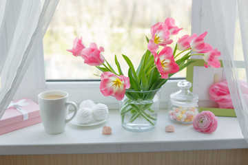 Fototapeta na wymiar a vase of flowers is on the window a Cup of tea marshmallows, a good morning card