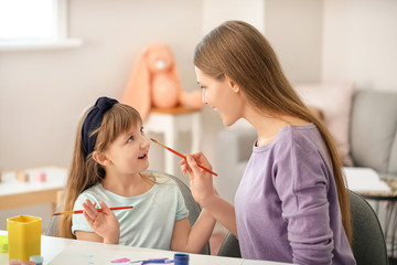 Drawing teacher giving private art lessons to little girl at home