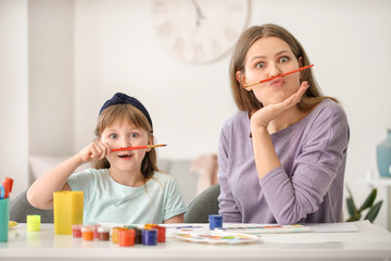 Drawing teacher and little girl having fun during private art lessons at home