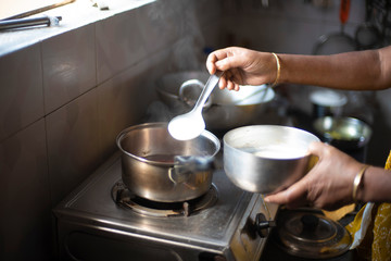 Tea being strained and poured into the cups from a steel tea pot in an Indian kitchen. Indian drink and beverages.