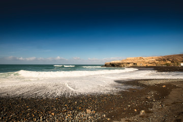 Black sand volcanic beach with wavea near fishing village Ajuy in Fuerteventura, Canary Islands, Spain