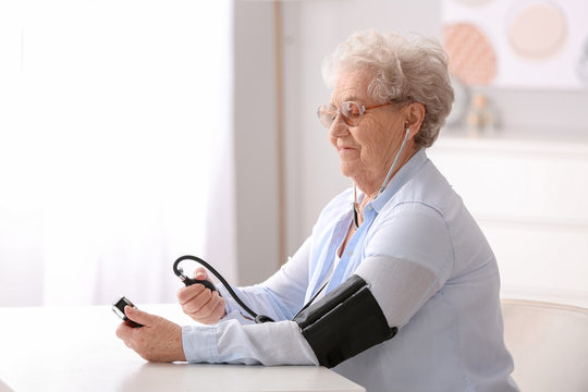 Elderly woman measuring blood pressure at home