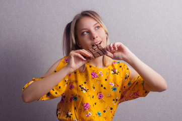 Teenager cute girl in yellow dress see on chocolate and want to eat it. Hungry