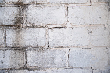 texture of a brick wall with a crack in the middle, mold on the left side. Building material in whitewash