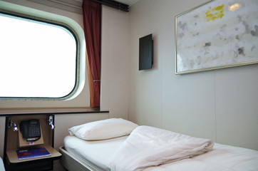 Oceanview cabin or exterior or outside stateroom with two single beds and large porthole in...