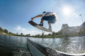 Wakeboarder jumps at ramp at wake park - obrazy, fototapety, plakaty