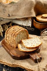 Bread on a wooden background, eggs, flour in a bowl, rye, bread knife, cereals