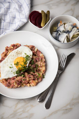Norddeutscher Hamburger Labskaus mit Rindfleisch Corned Beef, Rote Beete, Kartoffeln, Saure Gurken, Spiegelei und Rollmops auf Teller
