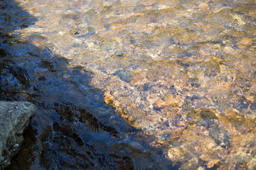 gravels under the clear rivulet water but with shadow