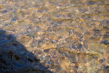 gravels under the clear rivulet water but with shadow