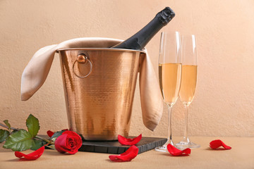 Bucket with ice and champagne on color background