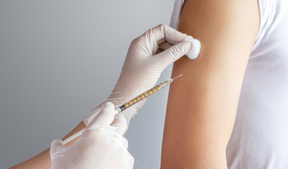 close-up of doctor, medical staff treating patient by injecting medicine in the upper arm at clinic or hospital. health care , treatment and vaccination concept