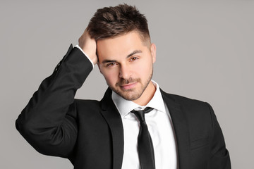 Portrait of handsome young businessman on grey background