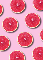 Grapefruit pattern on pink background. Top view. Creative design, minimal flat lay concept. Summer time. Tropical travel, exotic fruit. Vegan and vegetarian food