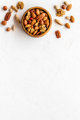 Mixed nuts in bowl on white background top-down frame copy space