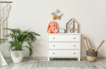 Chest of drawers with clothes and toys in children's room