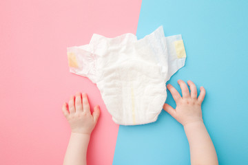 Baby hands and white diaper on light pink blue table background. Pastel color. Closeup. Point of...