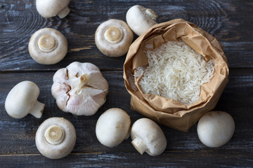 Fototapeta na wymiar Ingredients for a delicious vegan dish. White basmati rice, garlic and champignons on a wooden table, top view, horizontal