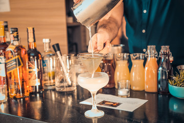 The expert bartender is making a cocktail at the bar. Man preparing cocktails.