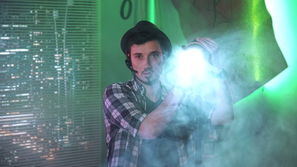 Medium shot of filmmaker looking at camera while using a Fresnel lamp. There is green background.