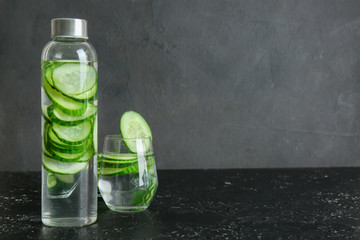 Glass and bottle of cucumber infused water on table