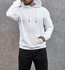 young man in white hoodie standing outdoors on gray background
