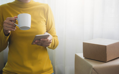Woman is freelancer with her private business at home office, working with phone and drink a...