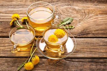 Cups of healthy dandelion tea on wooden background