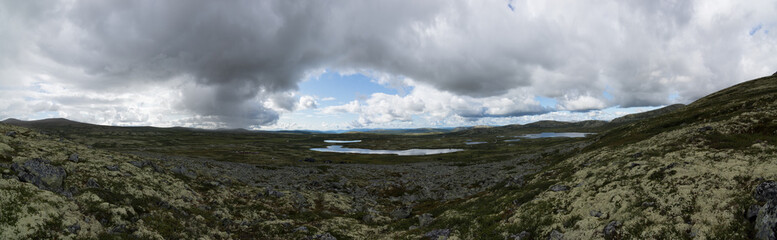 fjord and river in norway during summer with mountains and cloudy blue sky