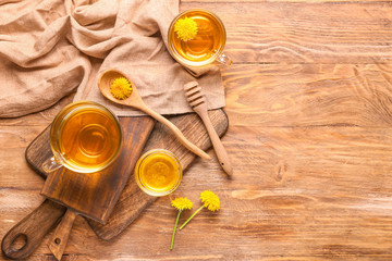 Cups of healthy dandelion tea with honey on table