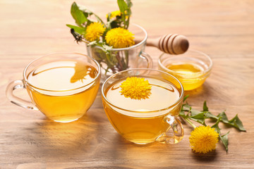 Cups of healthy dandelion tea with honey on table