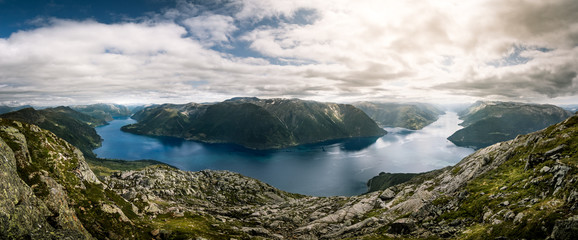 fjord and river in norway during summer with mountains and cloudy blue sky