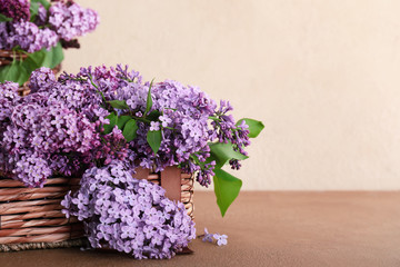 Basket with beautiful lilac flowers on table