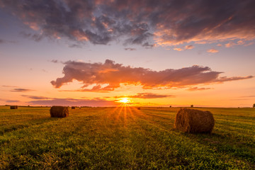 A field with haystacks on a summer or early autumn evening with a cloudy sky in the background....