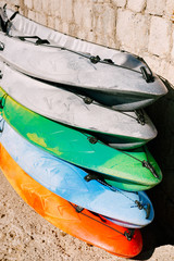 A warehouse of yellow, blue, green, grey kayaks on shore. Single kayaks. Rental kayakshop store on sandy beach