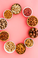 Nuts set in bowls on pink background top-down frame copy space mockup