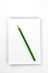 Open notebook with green Graphite pencil on a white office table