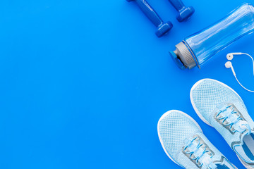 Fitness accessories. Dumbbells and sneakers on blue table top view copy space