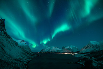 polar lights also called northern lights or aurora borealis in northern norway during winter above a fjord and snow covered mountains