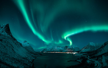 polar lights also called northern lights or aurora borealis in northern norway during winter above a fjord and snow covered mountains