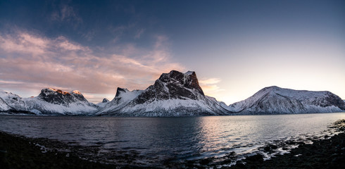 cold winter landscape in norway on the island senja with a scenic view over the fjord with warm light and clear sky
