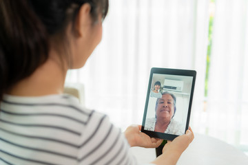 Asian young woman virtual happy hour meeting and talking online together with her mother in video conference with digital tablet for a online meeting in video call for social distancing..