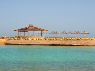 Stone spit with beach umbrellas in the sea