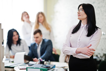 Portrait of caucasian woman in white blouse and eyeglasses against business people group of bank workers have meeting and working in modern office.