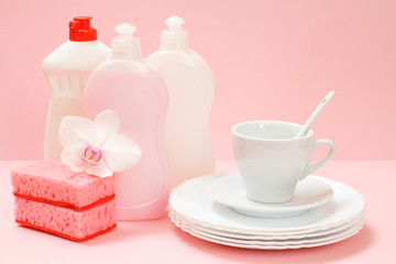 Fototapeta na wymiar Bottles of dishwashing liquid and utensil on a pink background.
