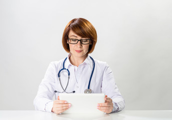 Redhead doctor using tablet computer in office