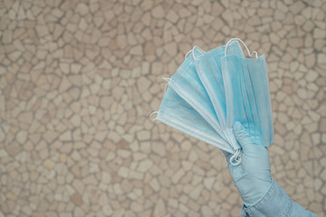 Hand in gloves holding protective masks isolated on gray background. place for textю