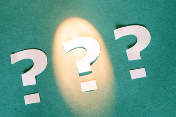 paper application three question marks on a paper background one of the signs is marked with light